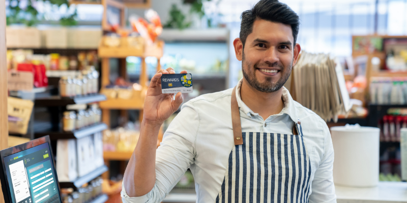 Store clerk holding up a loyalty rewards card. featured_image